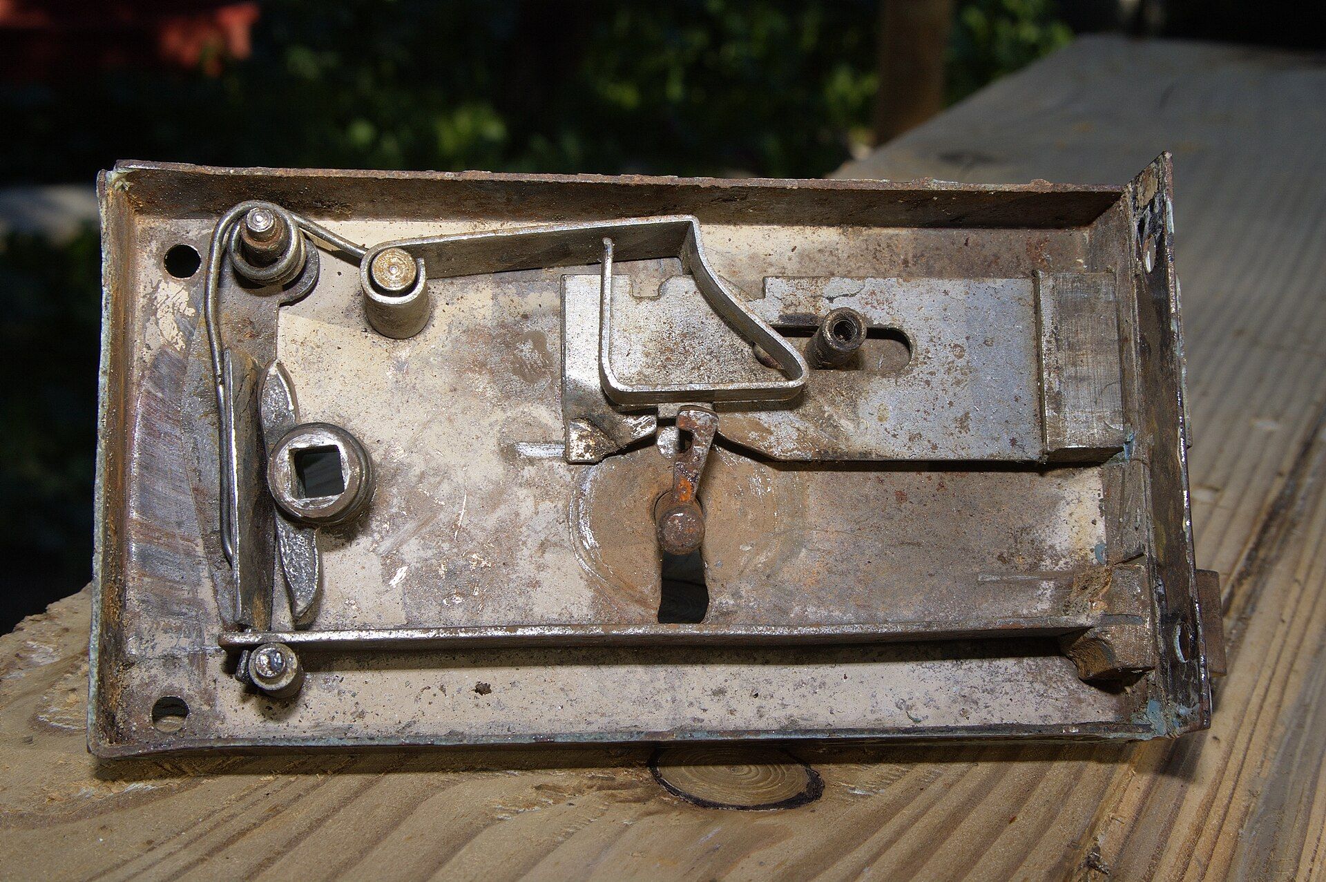 An old mortise door lock with its cover off, showing the spring, latch and bolt inside, for a theme in the writing of Richard Joseph Spinelli