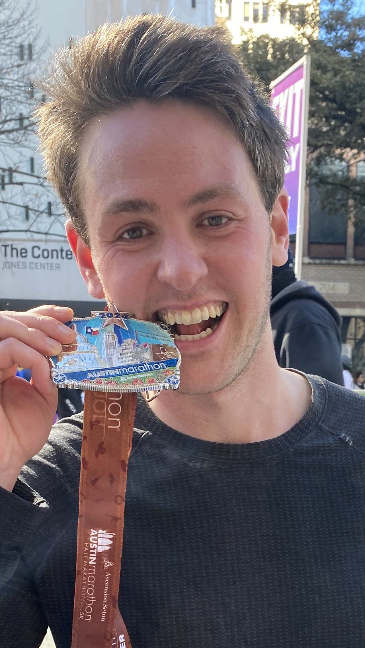 Richard Joseph Spinelli holding his finisher medal after the 2024 Austin Marathon, a waist up photograph